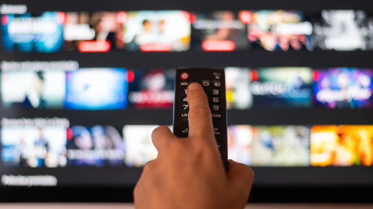 A person pointing a remote at a television streaming service